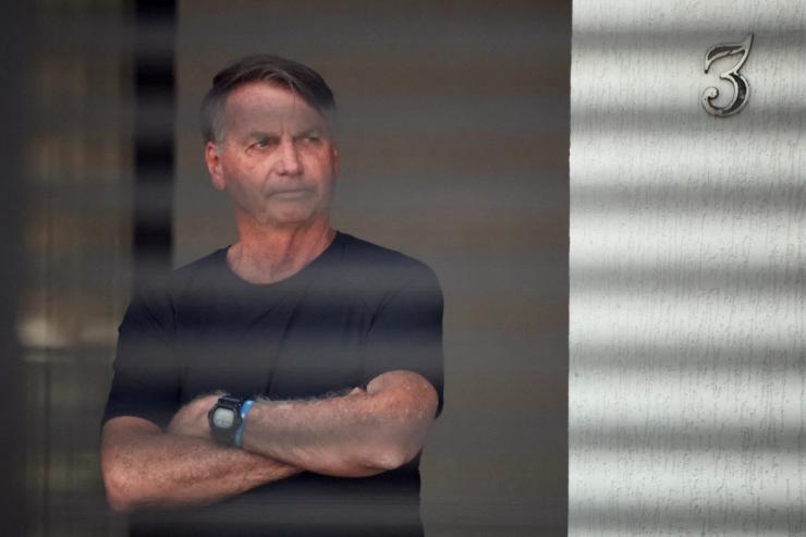 Brazil’s former President Jair Bolsonaro stands at his home while under house arrest.