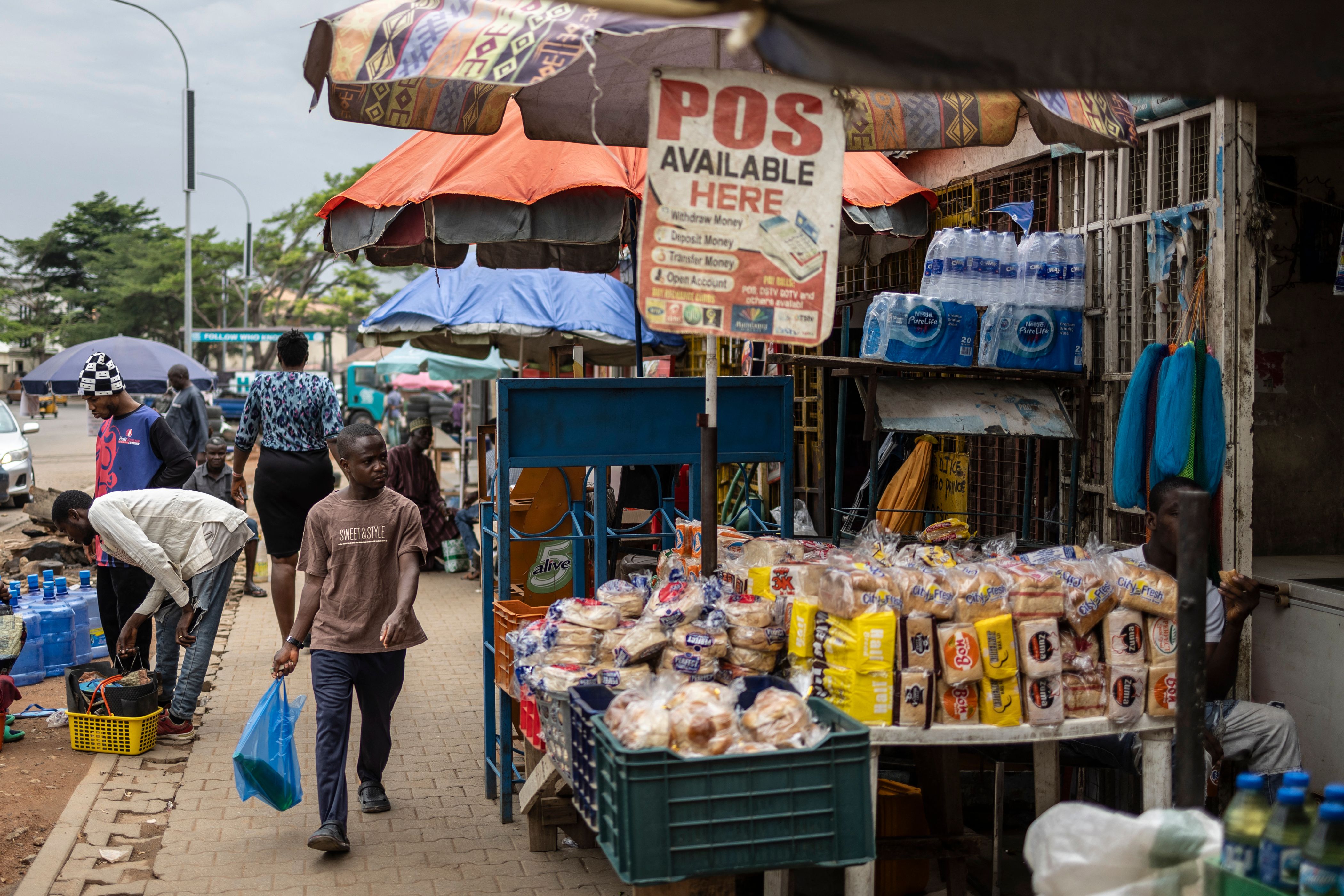 A man carrying shopping bags looks on as he walks past a shop in Jabi neighbourhood in Abuja.