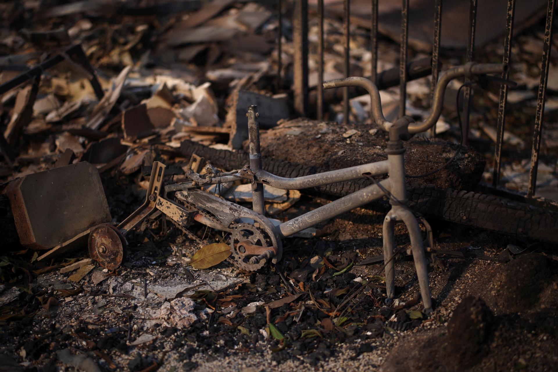 The remains of a burnt pedal vehicle stand amid debris in Los Angeles.