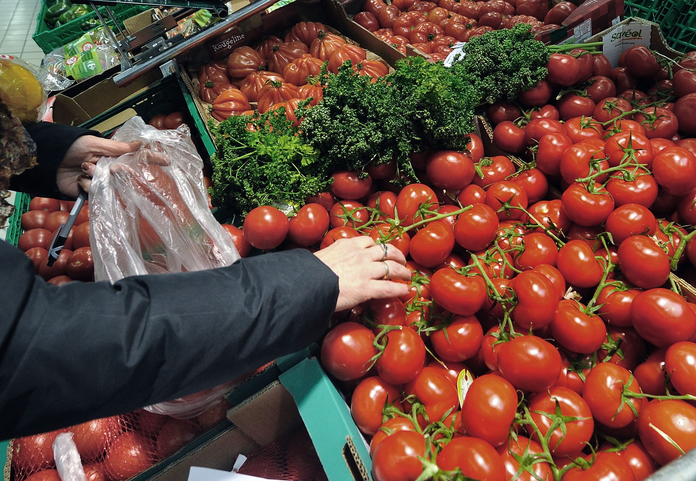 A woman shops tomatoes in the vegetables produce section of a Carrefour supermarket.