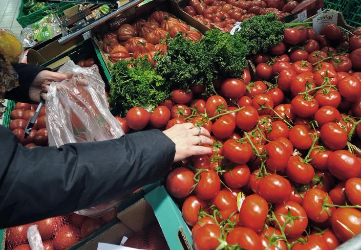 A woman shops tomatoes in the vegetables produce section of a Carrefour supermarket.