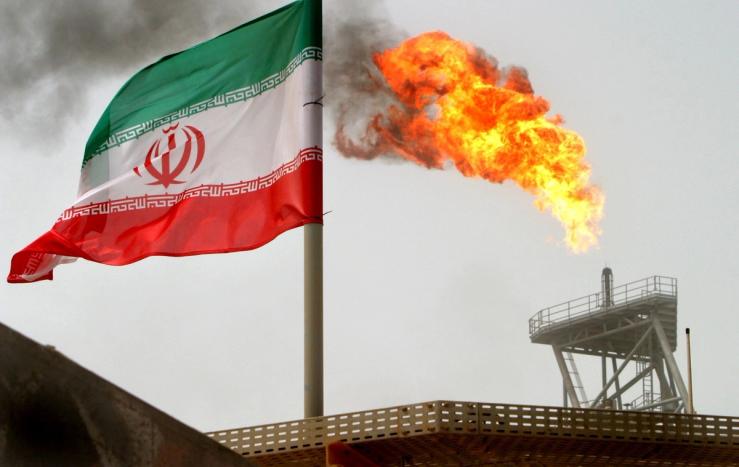 A gas flare on an oil production platform is seen alongside an Iranian flag.