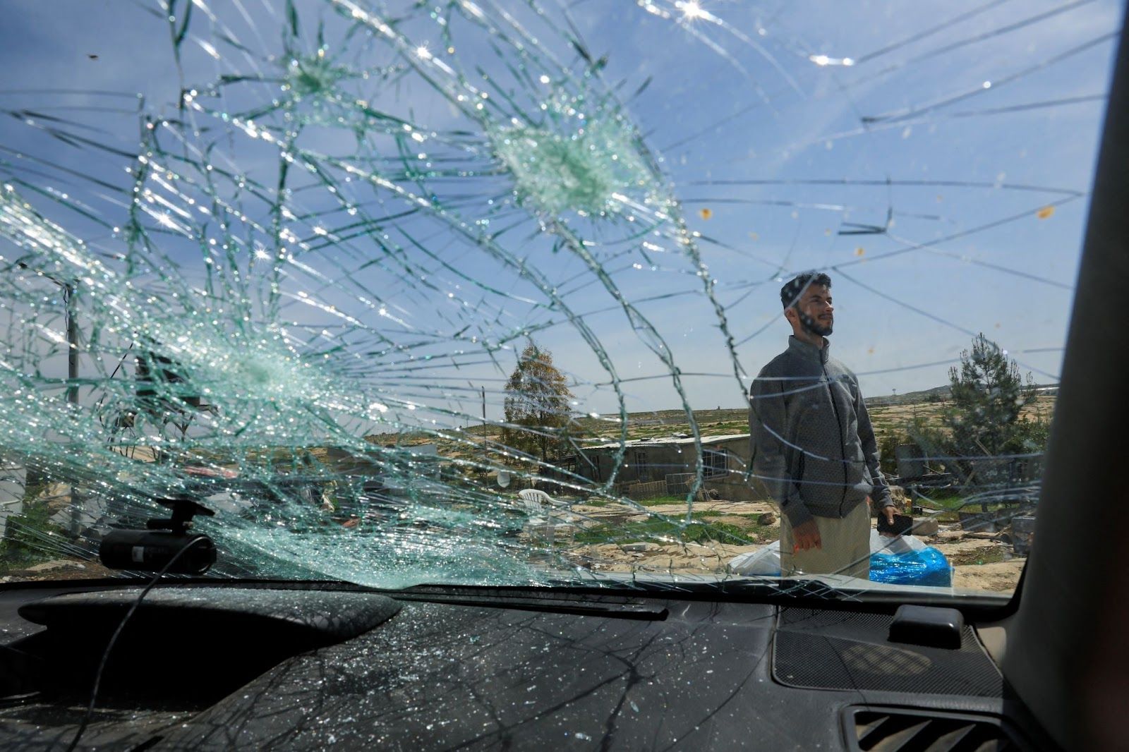 One of the directors of No Other Land checks a damaged car after an attack by Israeli settlers. 