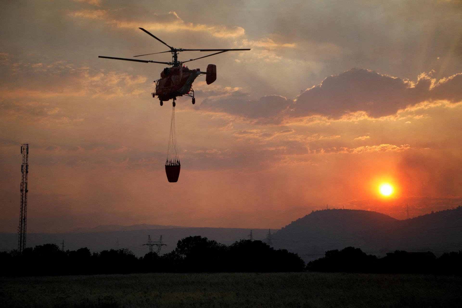 A firefighting helicopter flies over Rogami suburb during sunset, as temperature rises during a heatwave in Podgorica, Montenegro