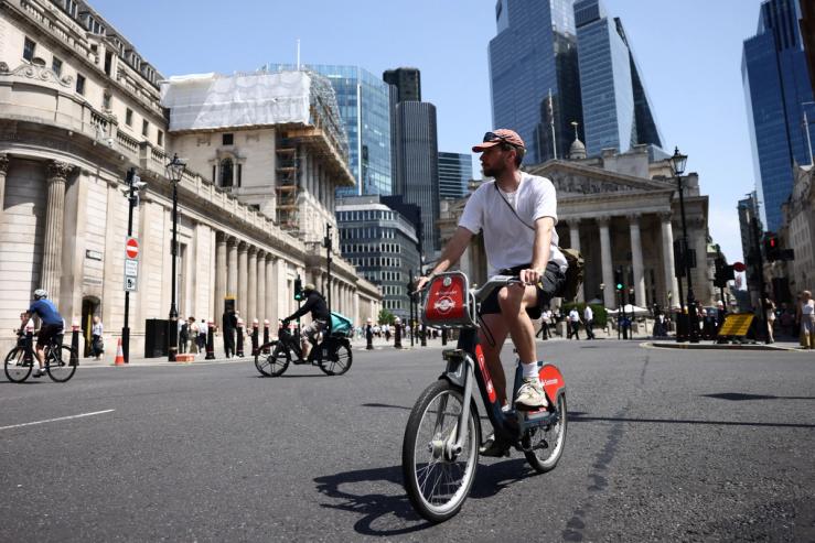 A man cycles past the Bank of England as Britain experiences record temperatures.