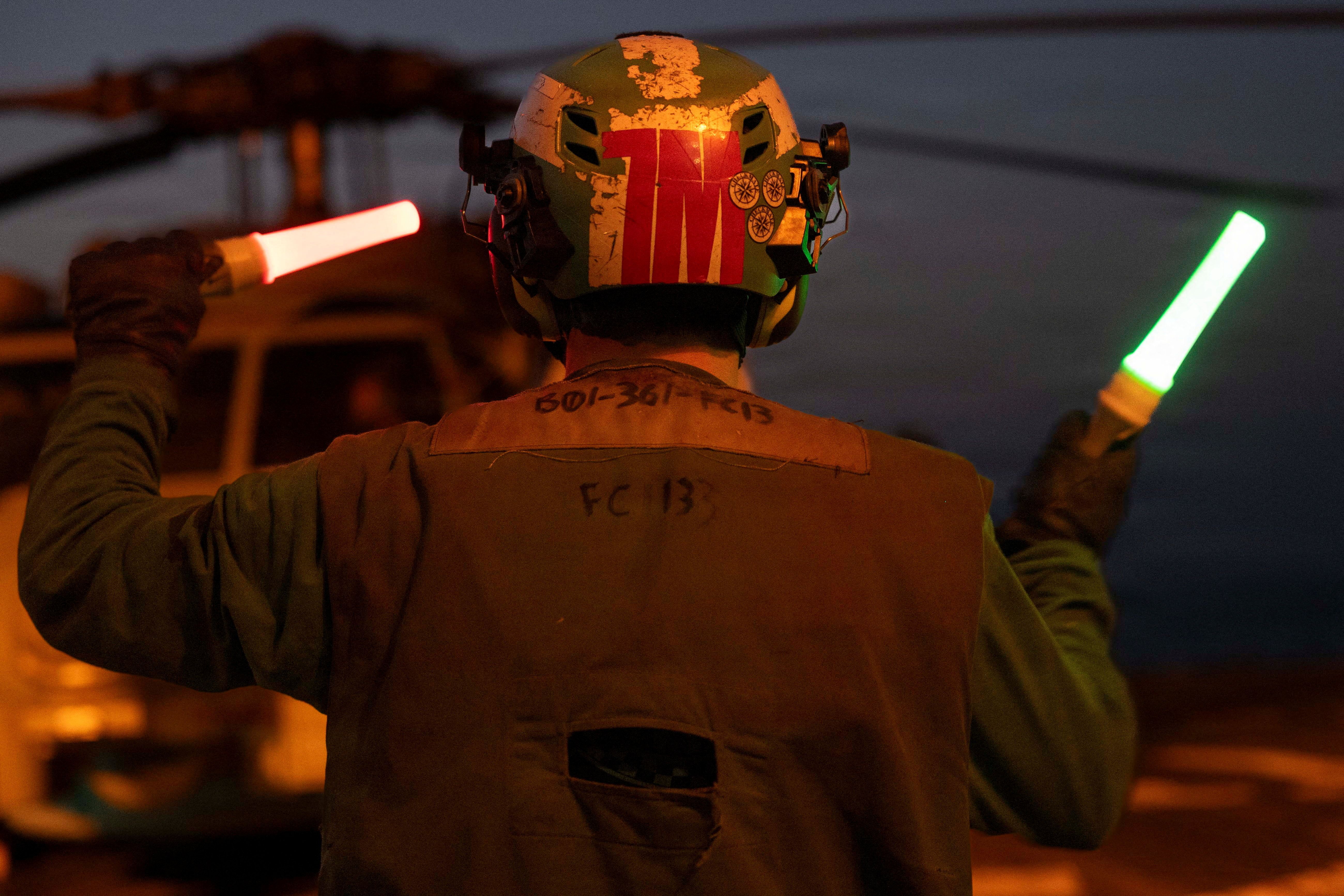A U.S. sailor, assigned to Arleigh Burke-class guided-missile destroyer USS Delbert D. Black, directs an MH-60R Sea Hawk helicopter, attached to Helicopter Maritime Strike Squadron (HSM) 46, during a flight quarters evolution for a mission supporting Operation Epic Fury during the Iran war at an undisclosed location, March 18, 2026.