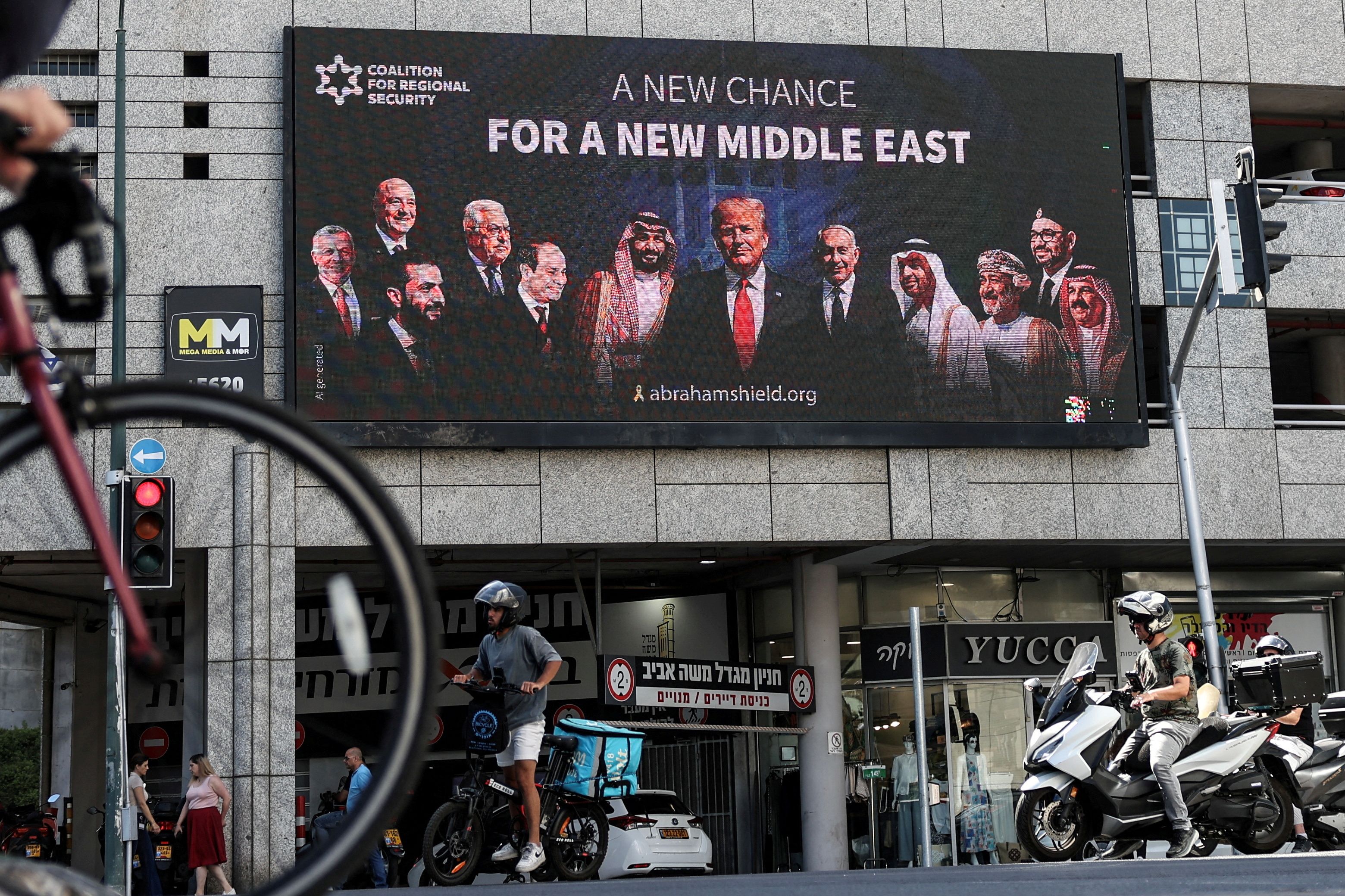 People walk by a billboard calling for the expansion of the Abraham Accords