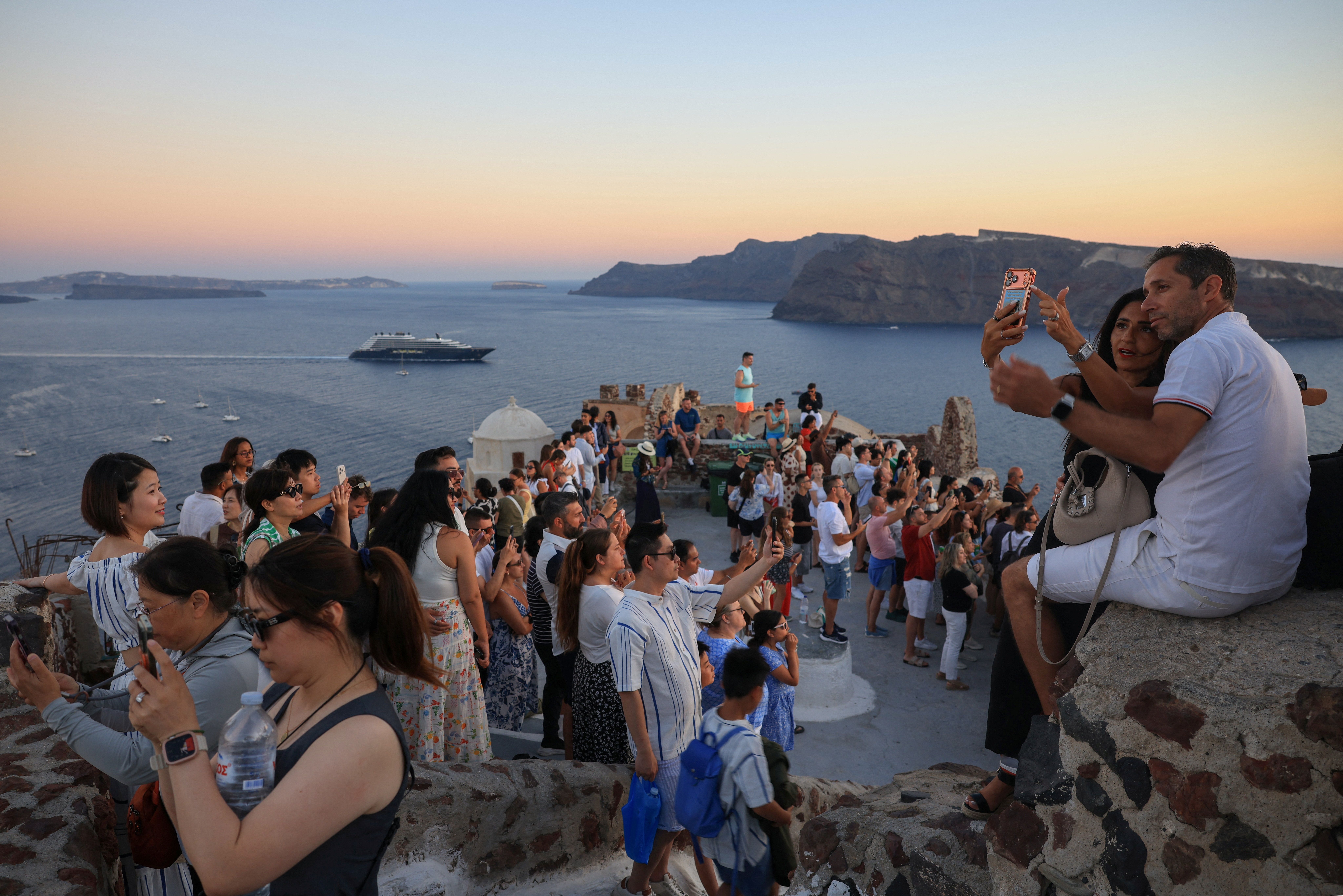 Tourists gather at the castle to watch the famous sunset in the village of Oia, on the island of Santorini, Greece