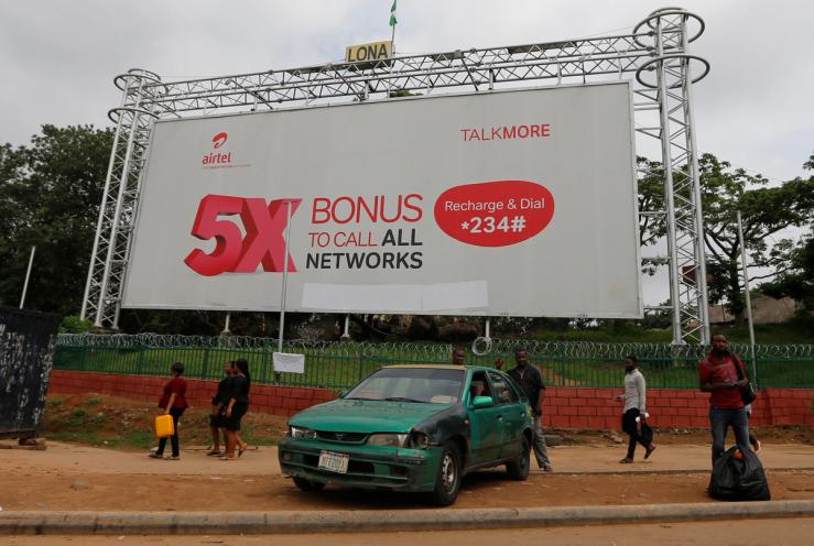 People walk past a billboard for telecommunications company Airtel in Abuja, Nigeria.