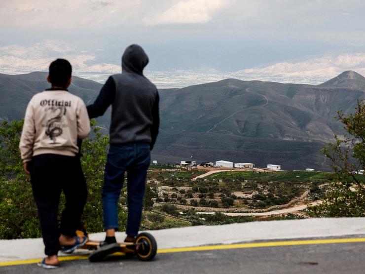 Palestinian children look at new Israeli settlement.