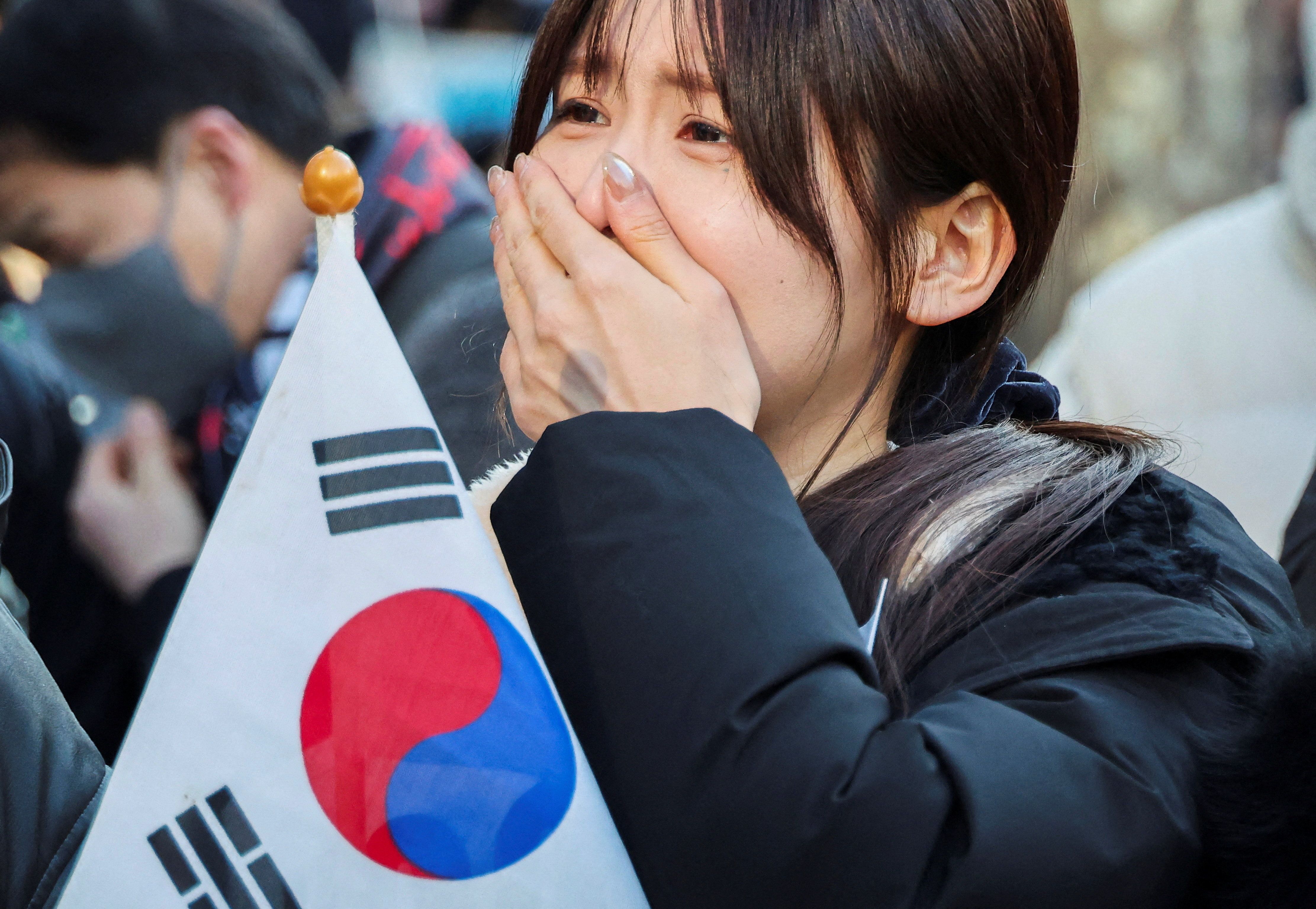 A supporter of former South Korean President Yoon Suk Yeol reacts to the news that he was sentenced to life in prison for insurrection, in Seoul. 