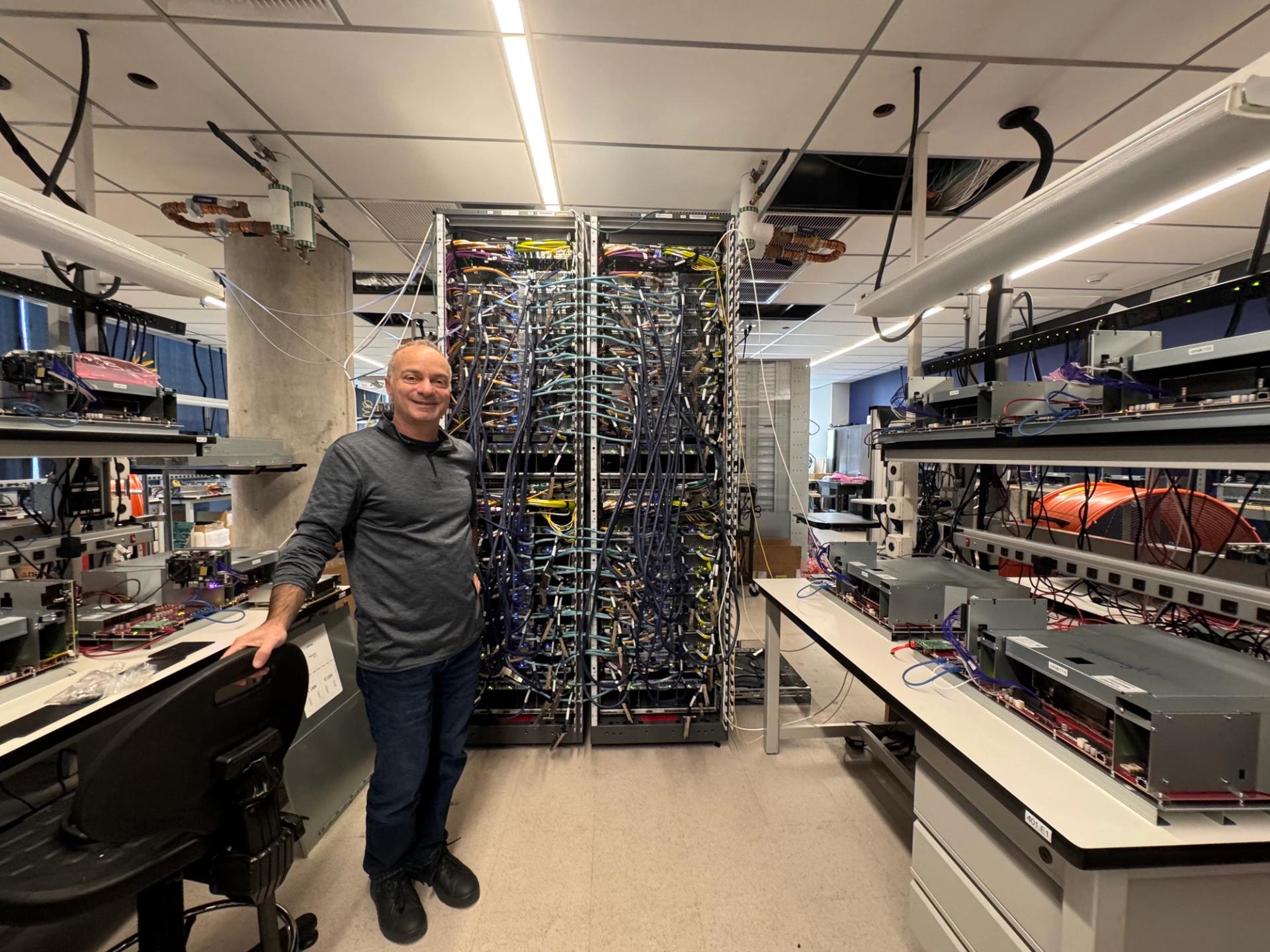 Rami Sinno, director of engineering for Annapurna Labs, standing in front of a rack of Trainium chips undergoing testing at its Austin lab.