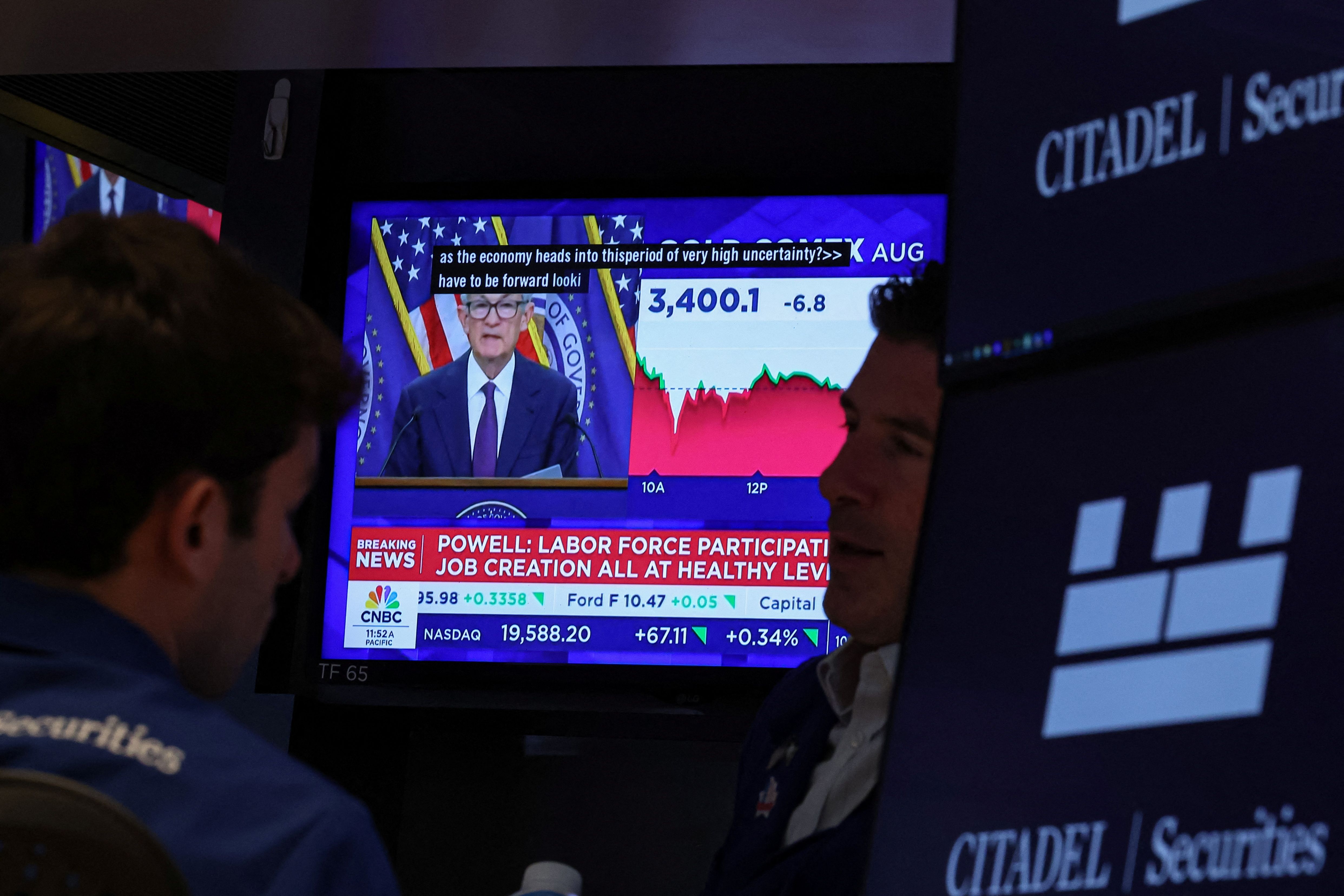Traders watch as Jerome Powell gives a press conference