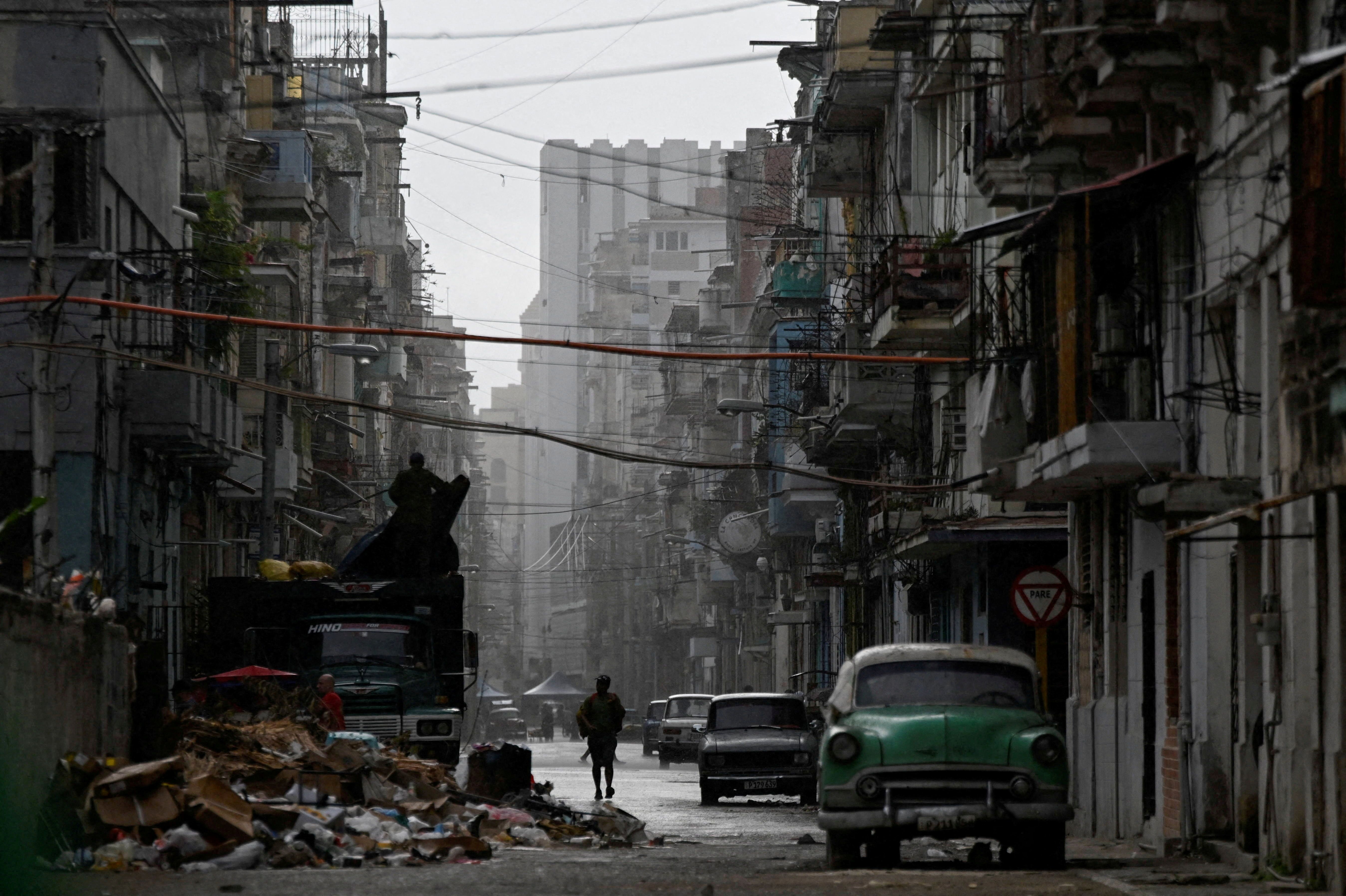 A man walks on a street in the rain as Cuba reconnected its electrical grid across much of the island.