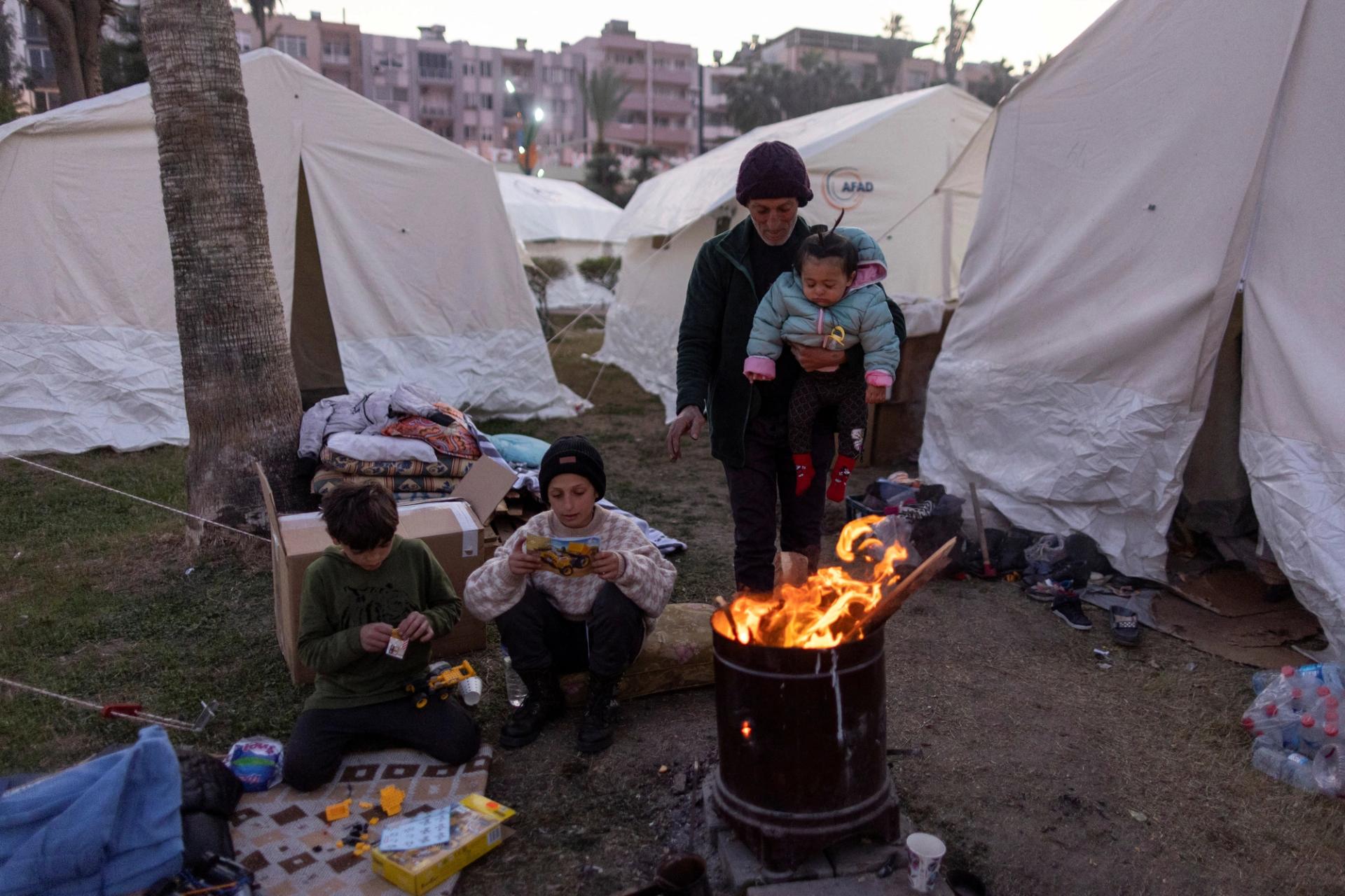 A Syrian family gathers around a fire for warmth, at a park turned into a camp for displaced people, following the deadly earthquake, in Iskenderun city, Hatay province, Turkey, February 14, 2023