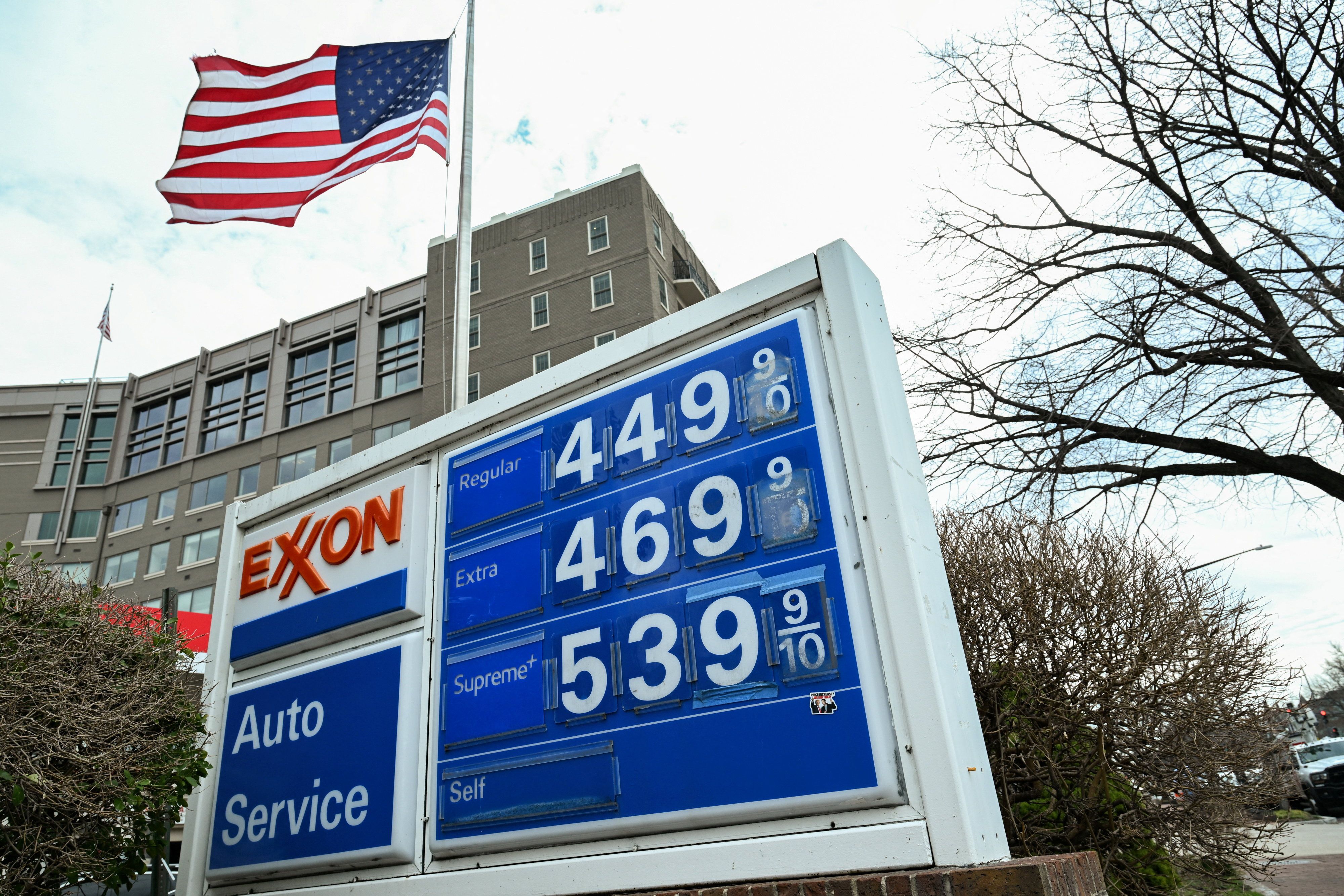 The American flag waves behind a board displaying gas prices 