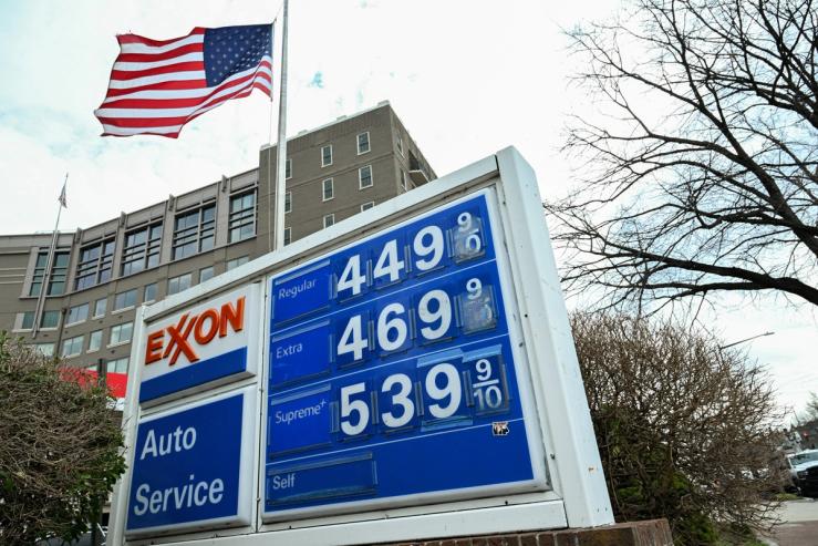 The American flag waves behind a board displaying gas prices