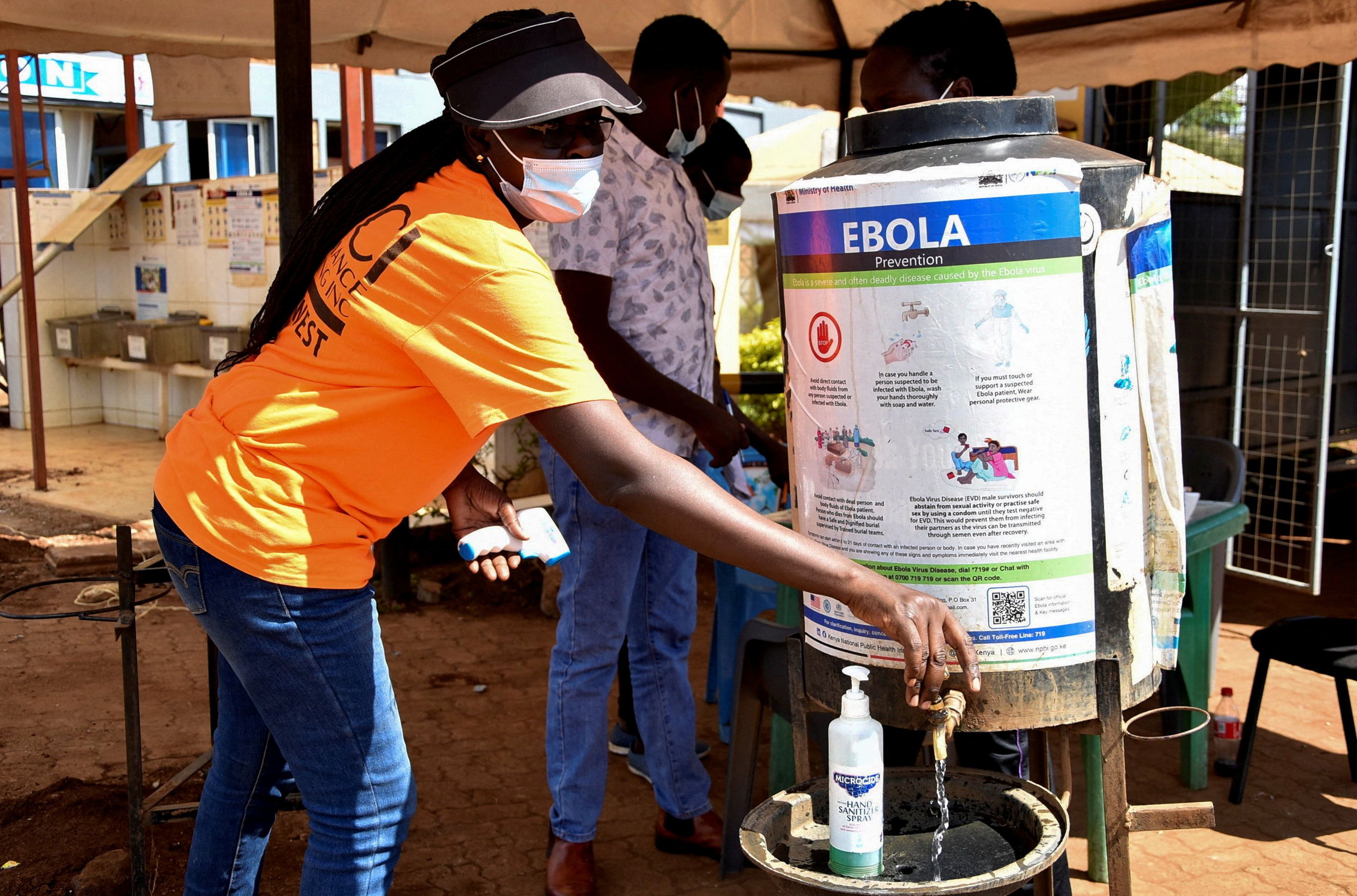 A medical worker controls the sanitization point for travellers to wash their hands before entering the Kenya immigration services