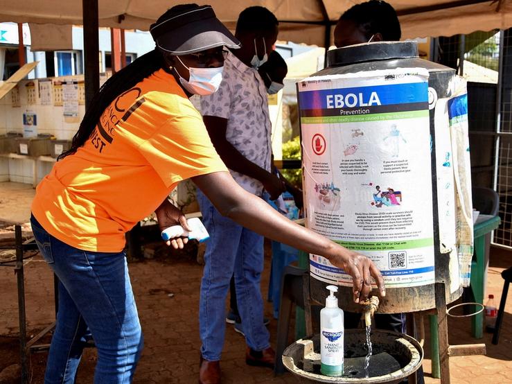 A medical worker controls the sanitization point for travellers to wash their hands before entering the Kenya immigration services