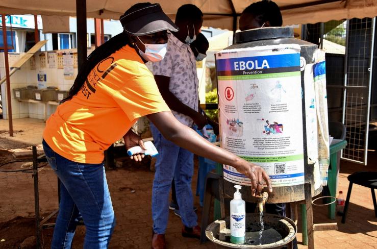 A medical worker controls the sanitization point for travellers to wash their hands before entering the Kenya immigration services