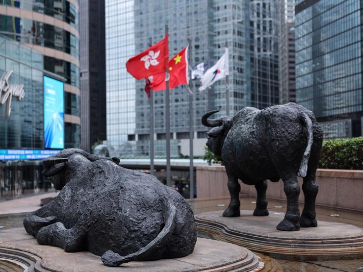 Bull statues near screens showing the Hang Seng stock index and stock prices outside Exchange Square, in Hong Kong.