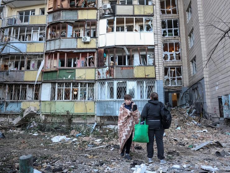 Residents stand amidst the rubble of a building in Kyiv that was destroyed by a Russian missile strike on August 20, 2026