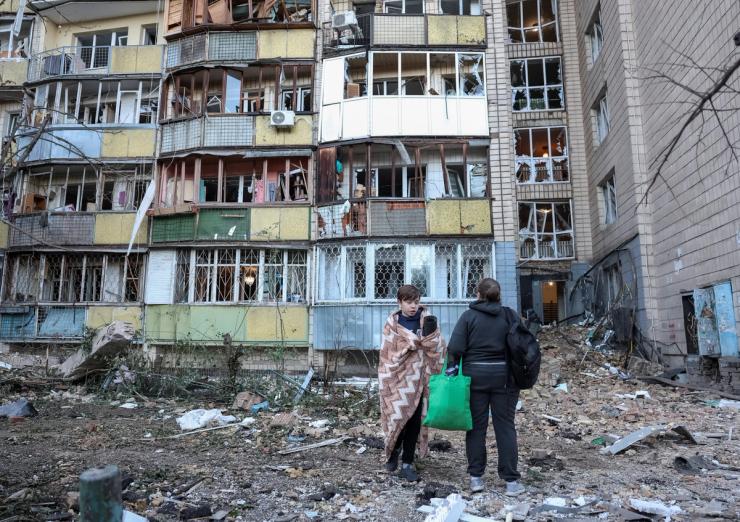 Residents stand amidst the rubble of a building in Kyiv that was destroyed by a Russian missile strike on August 20, 2026