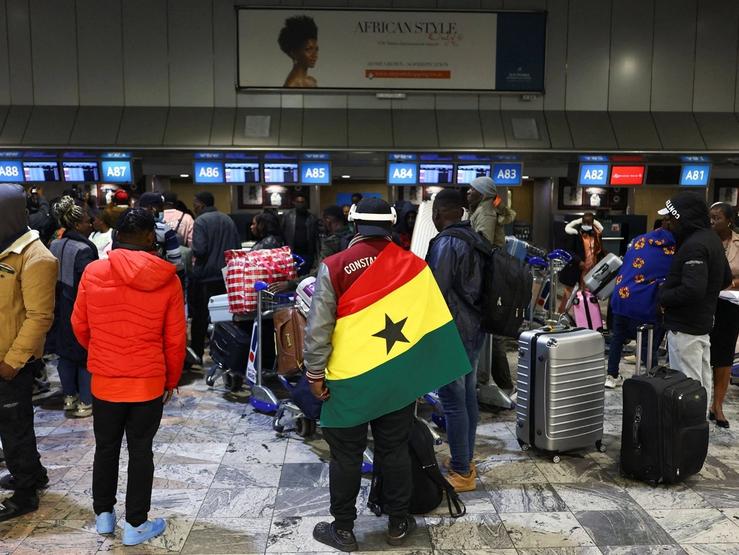 A man draped in a Ghana flag waits to be repatriated from South Africa.