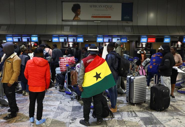 A man draped in a Ghana flag waits to be repatriated from South Africa.