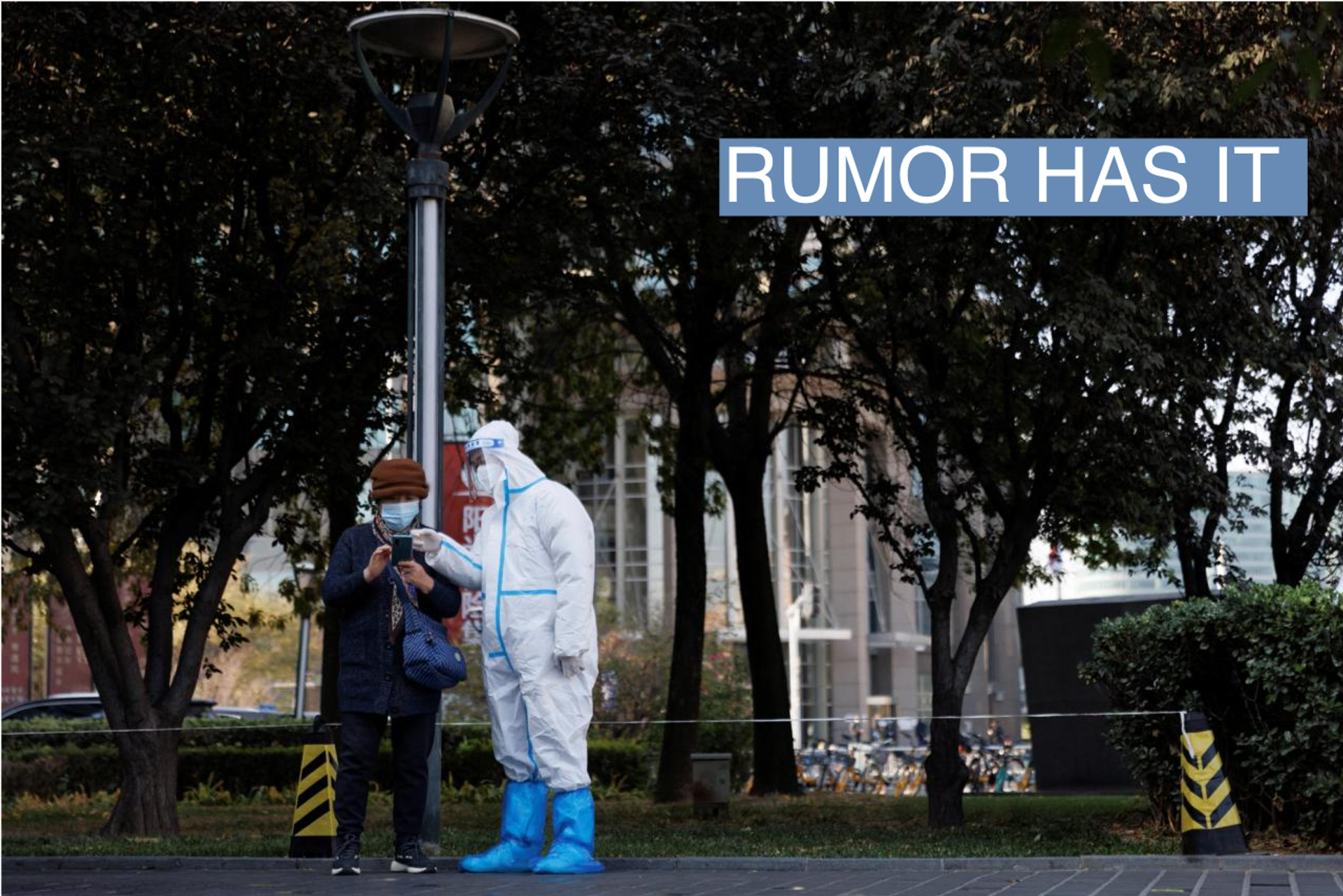 A pandemic prevention worker wears a protective suit as he checks personal details of a woman lining up to get a swab test at a testing booth as outbreaks of coronavirus disease (COVID-19) continue in Beijing, China