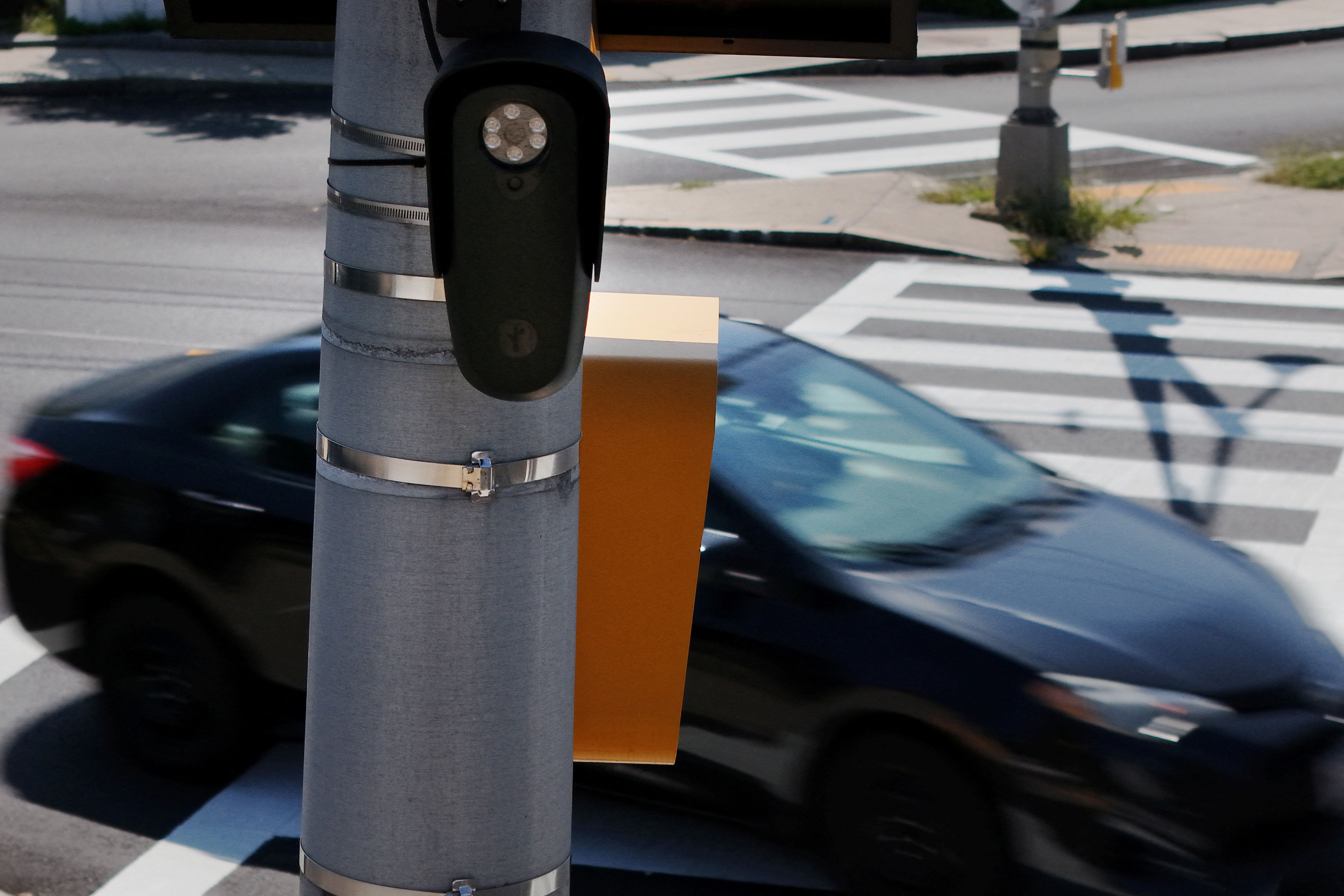 A drone view shows a Flock Safety camera mounted on a pole beneath a solar panel in Malden, Massachusetts