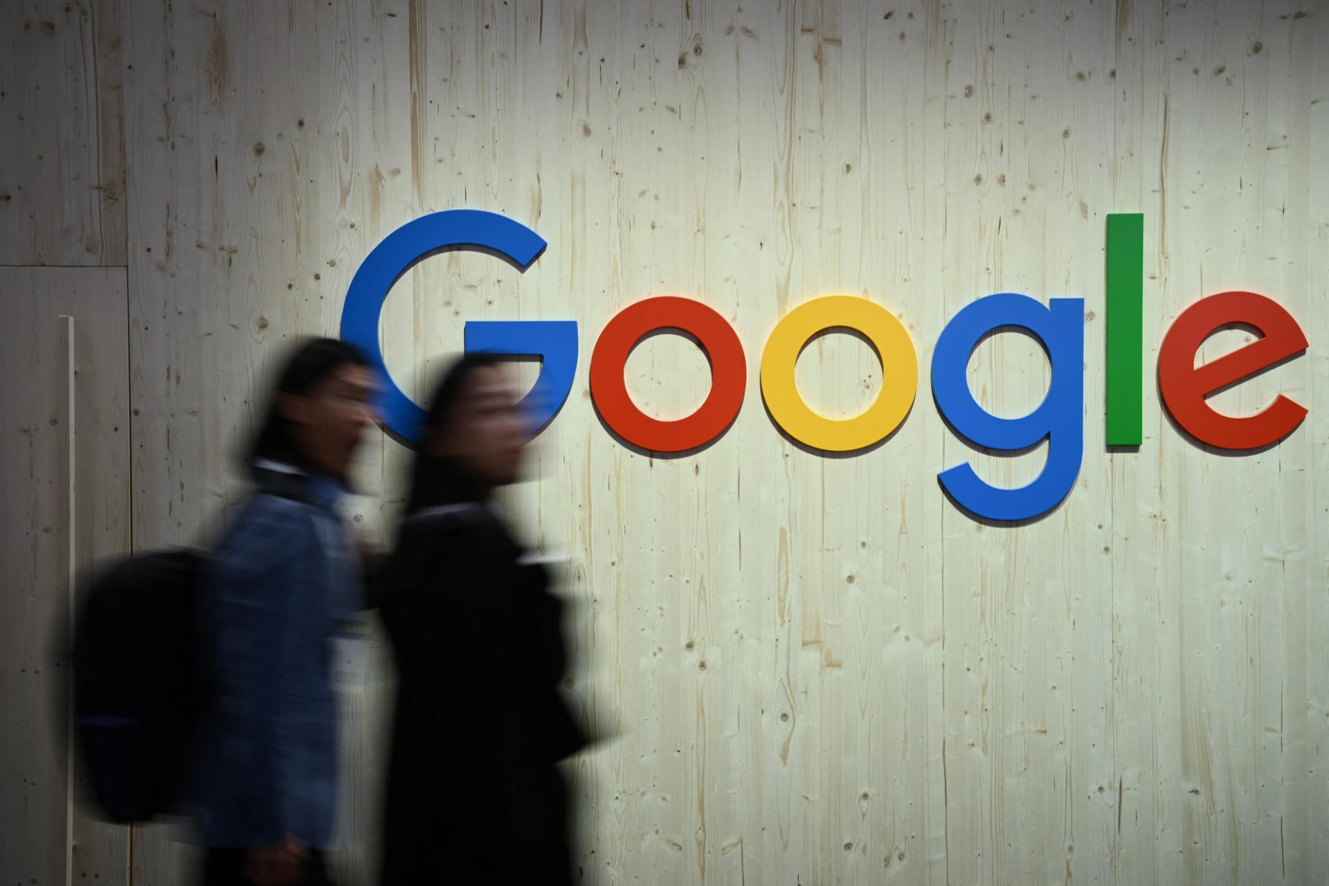 People walk next to a Google logo.