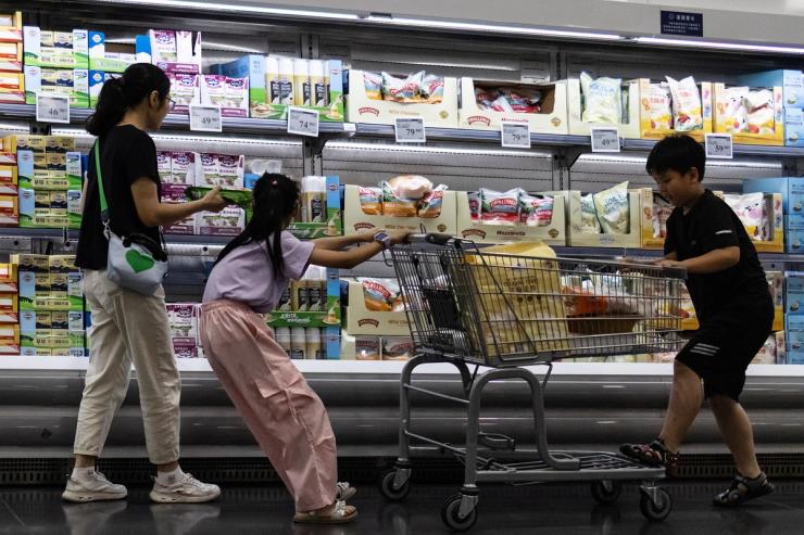 A woman and two children shop in front of a refrigerated cheese shelf at a supermarket in Beijing, China.