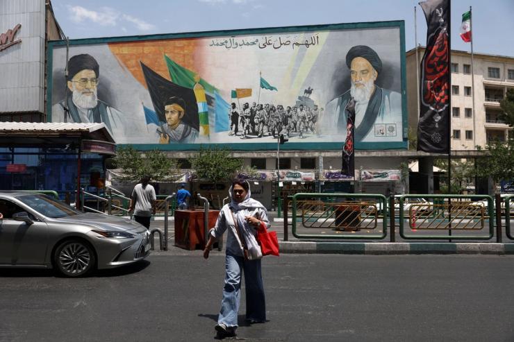 A woman walks near a mural depicting the late leader of the Islamic Revolution.