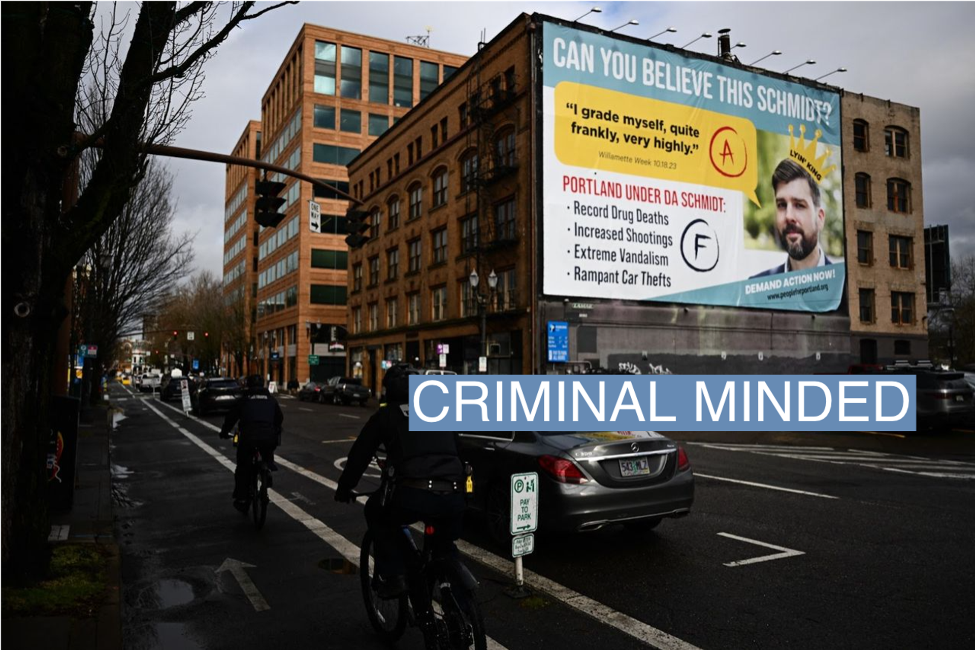 Oregon State Trooper law enforcement officers bicycle past a billboard from the People for Portland Campaign, targeting Multnomah County District Attorney Mike Schmidt and declaring "Portland is a Schmidt Show!" in downtown Portland, Oregon, on Jan. 24, 2024. 