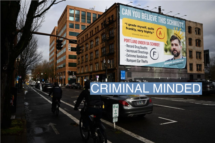 Oregon State Trooper law enforcement officers bicycle past a billboard from the People for Portland Campaign, targeting Multnomah County District Attorney Mike Schmidt and declaring “Portland is a Schmidt Show!” in downtown Portland, Oregon, on Jan. 24, 2024.