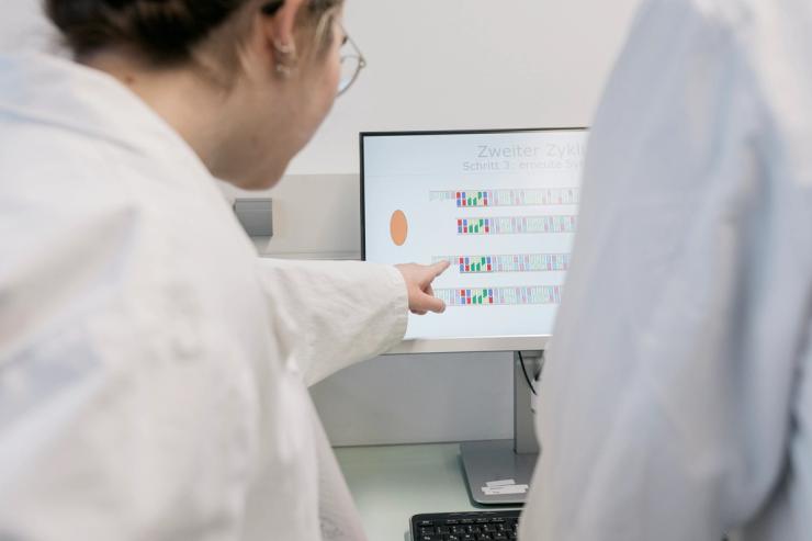Some medical students looking at DNA base pairs on a computer screen after doing an experiment in the lab together.