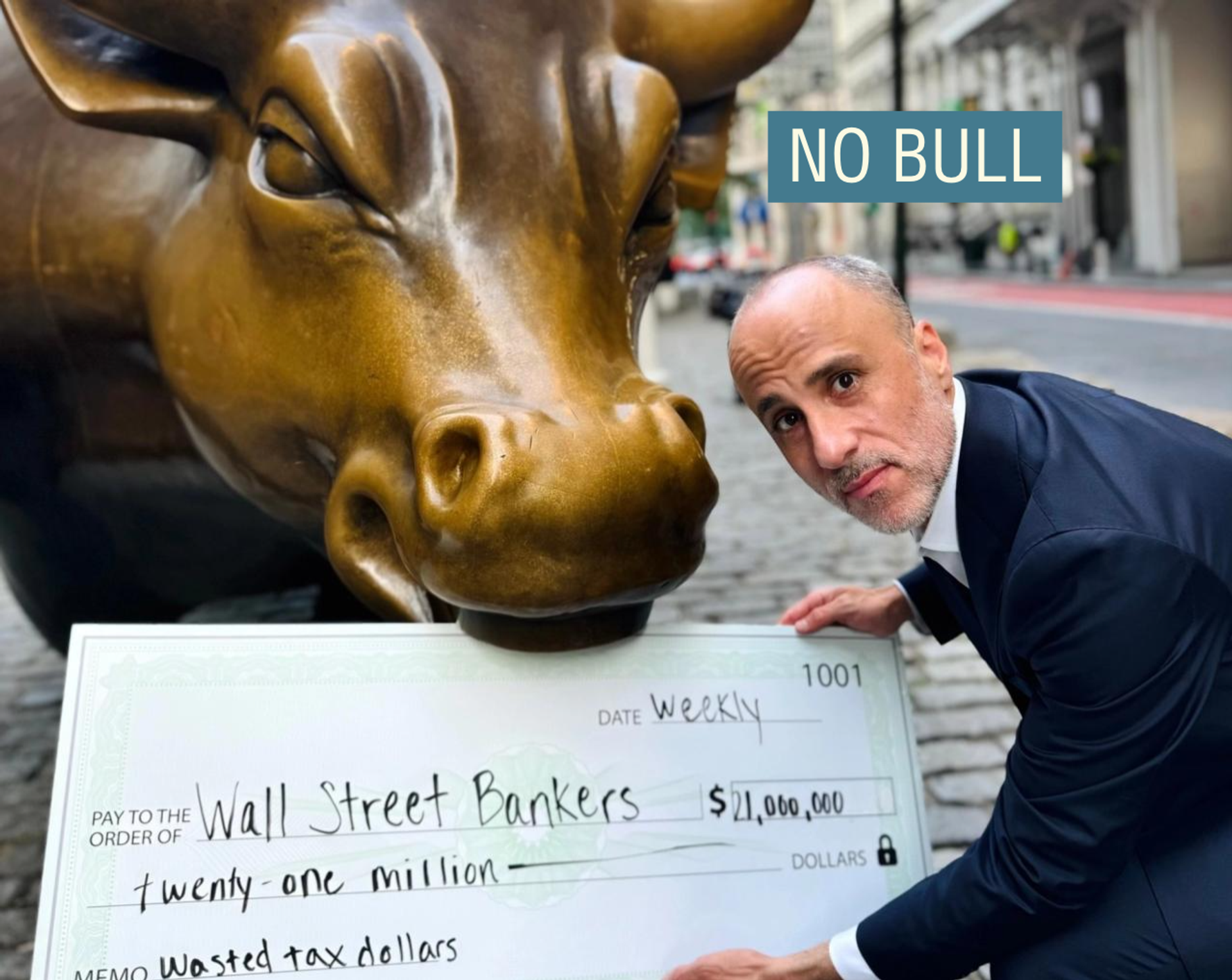 Drew Warshaw holding a check next to Wall Street’s bronze bull.