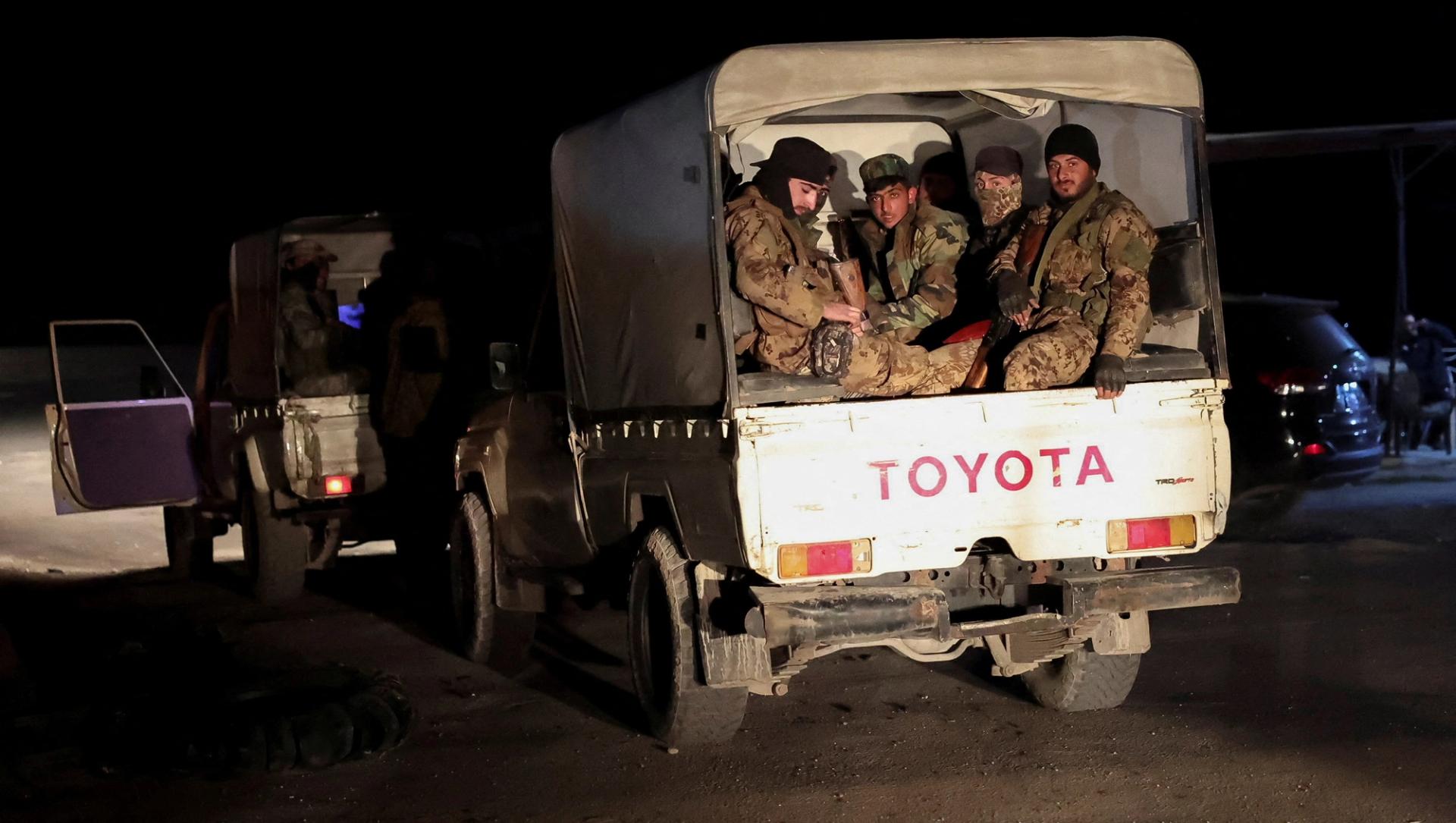 Syrian forces ride on military vehicles as they head to Latakia Thursday.