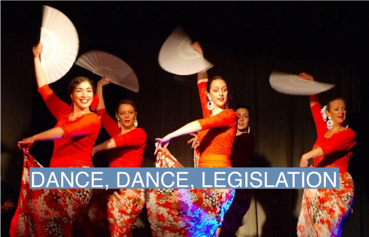 Flamenco dancers dressed in red and floral patterns wave fans and perform a routine.