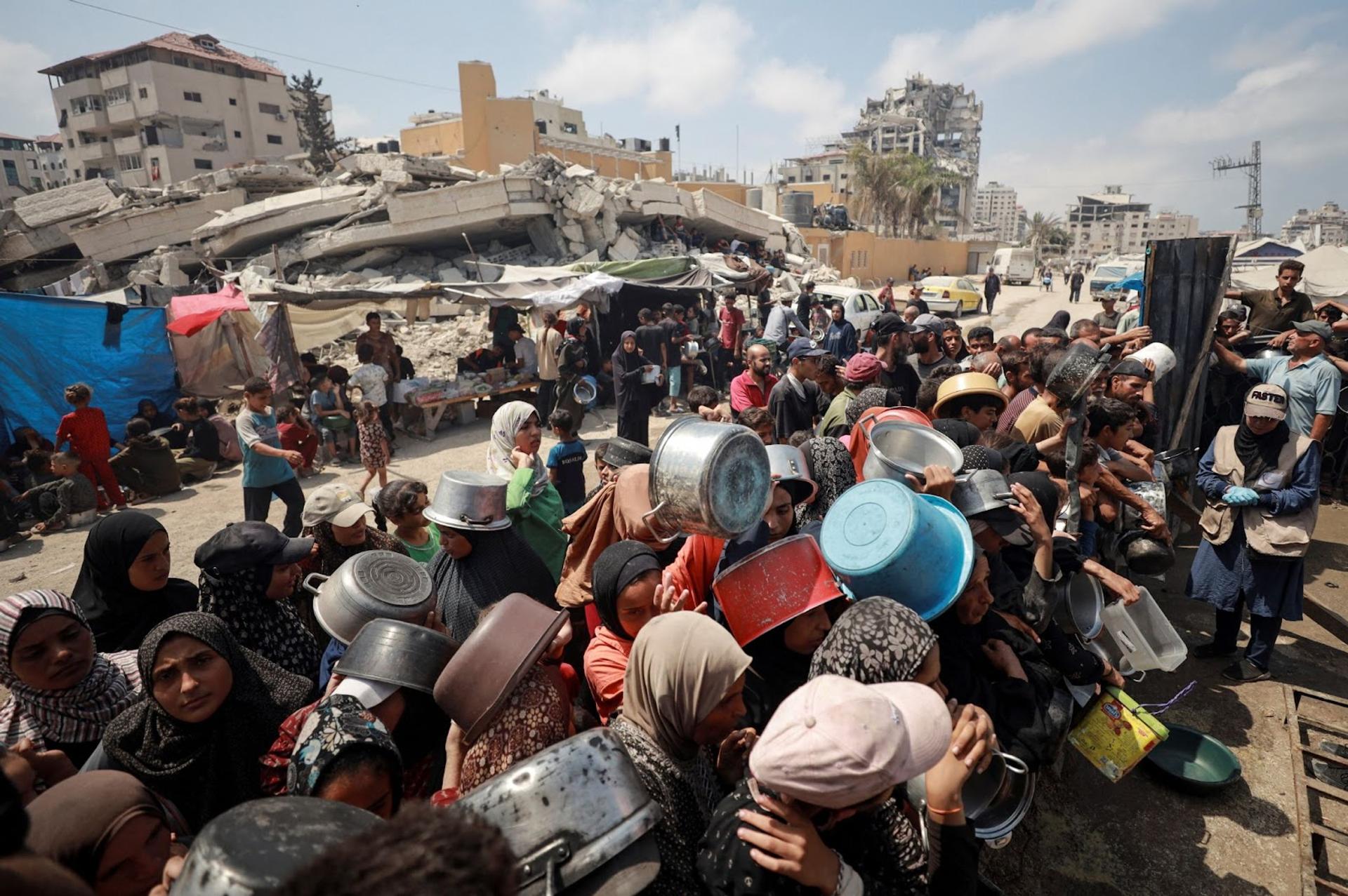 Gazans hold out vessels for food.