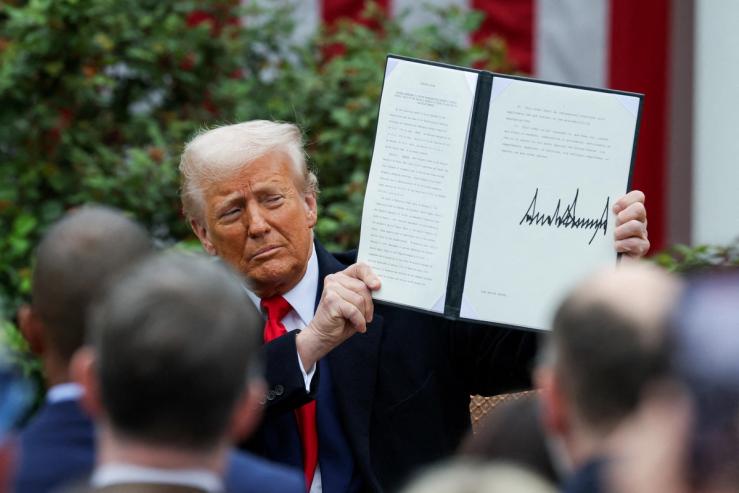 US President Donald Trump holds a signed executive order, on the day he delivers remarks on tariffs in the Rose Garden at the White House in Washington, April 3 2025.