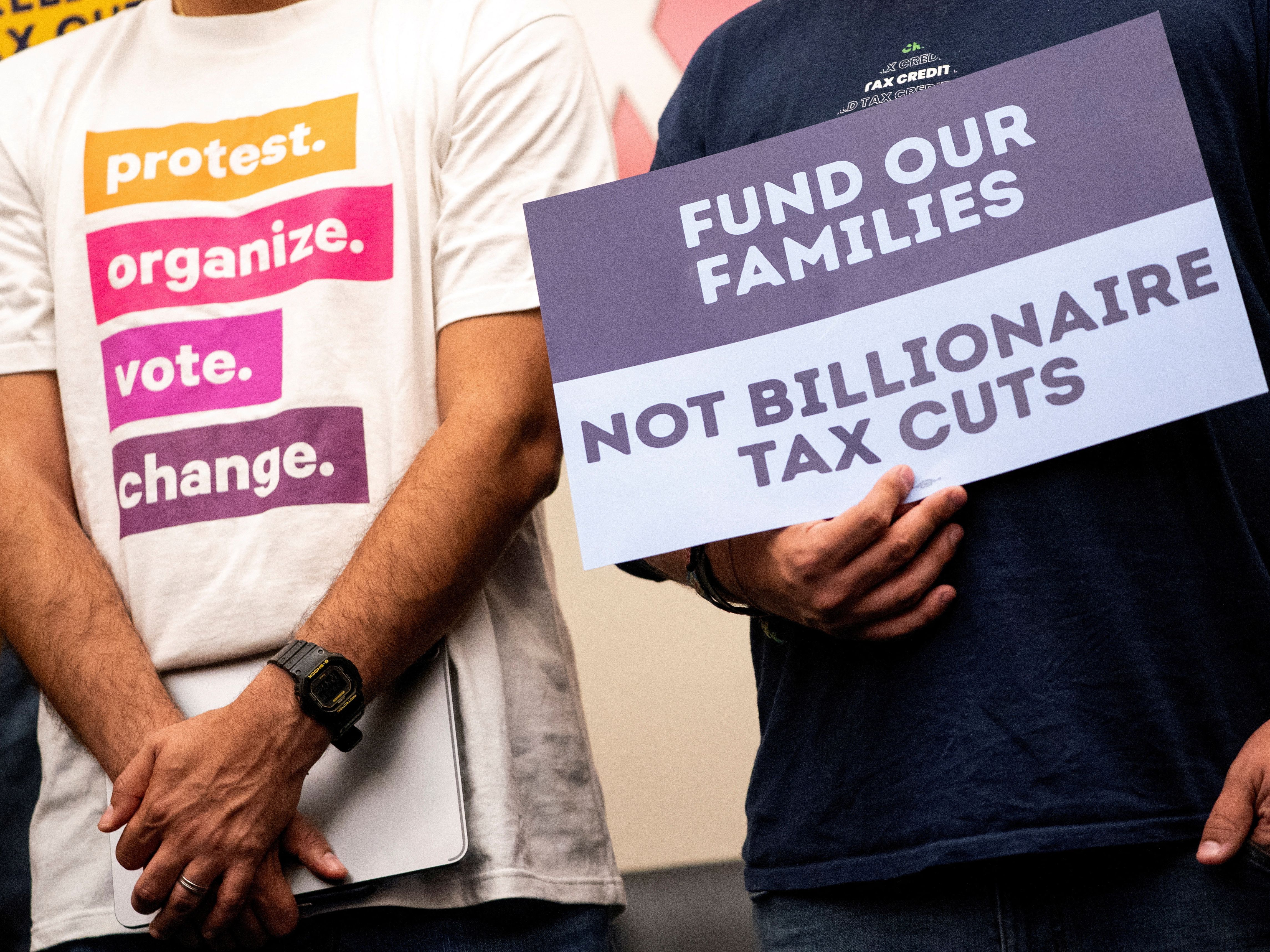 A person with a sign protesting “billionaire tax cuts” 