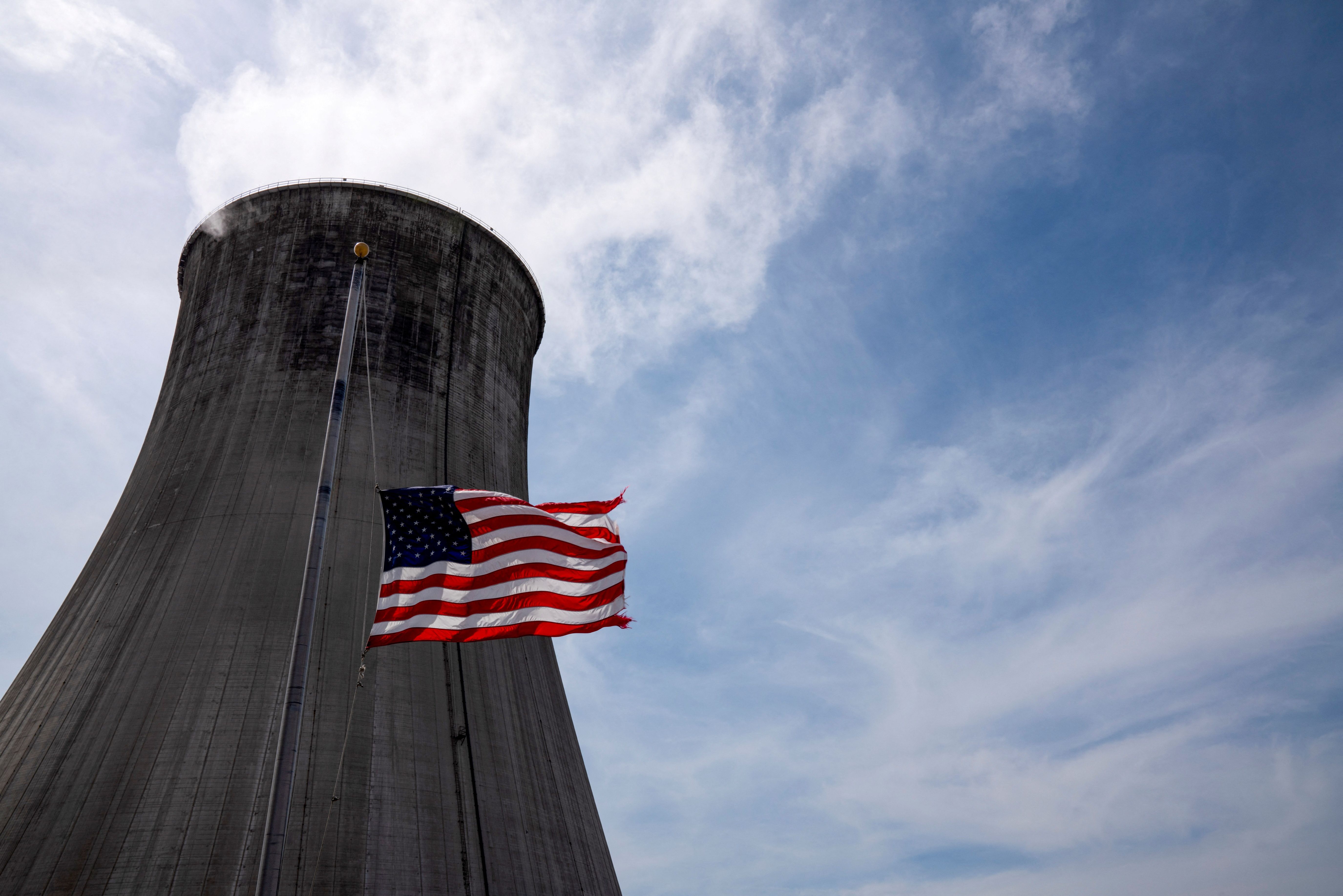 The US flag flies at half mast in front of a coal-fired power plant’s cooling tower at Duke Energy’s Crystal River Energy Complex in Crystal River, Florida