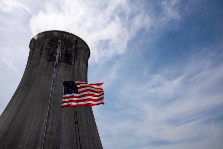The US flag flies at half mast in front of a coal-fired power plant’s cooling tower at Duke Energy’s Crystal River Energy Complex in Crystal River, Florida