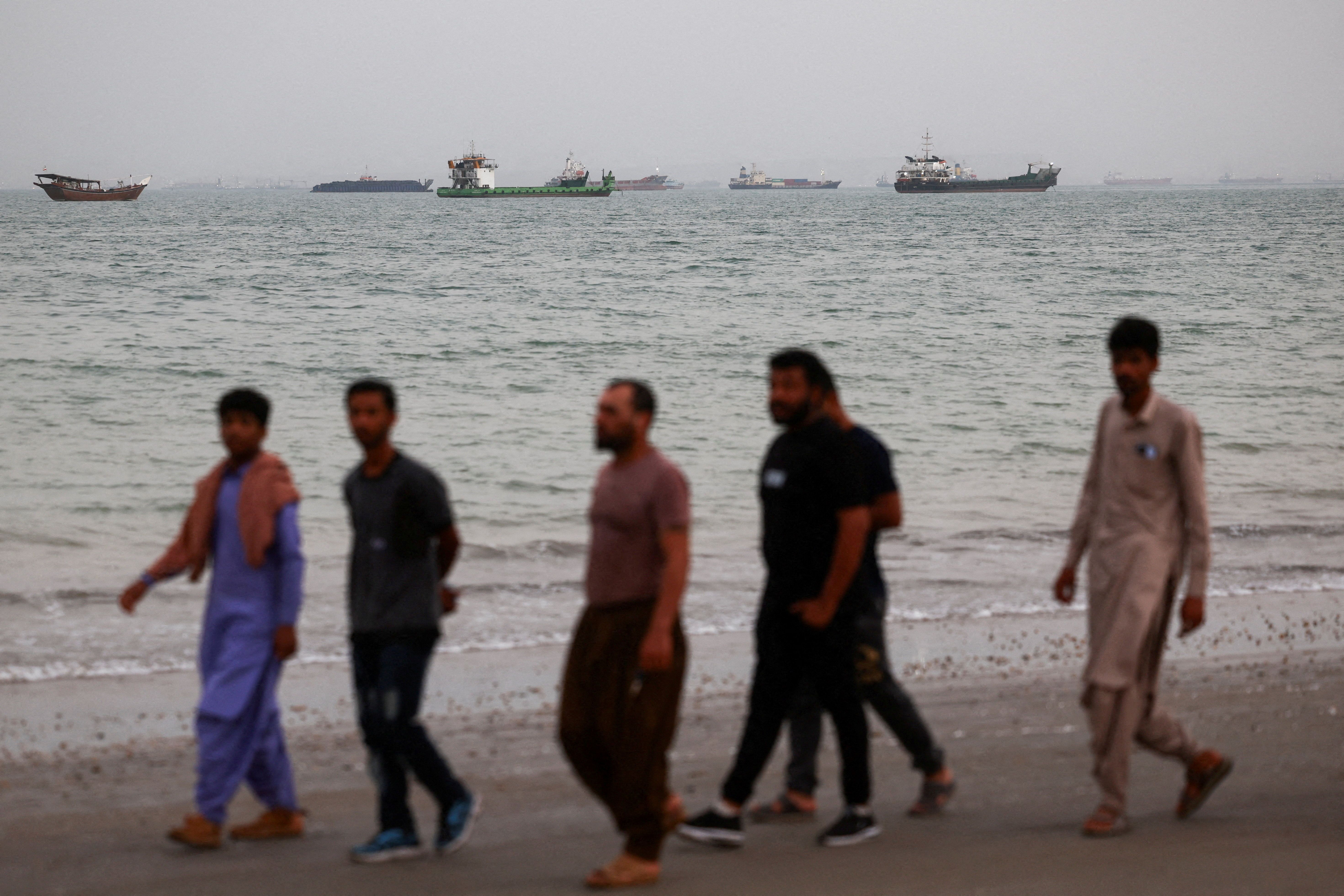 Men walk on the beach in Bandar Abbas, Iran