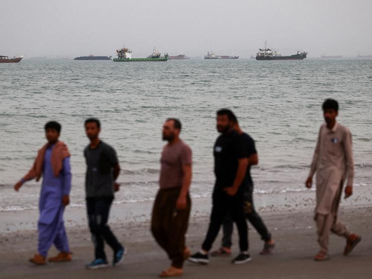 Men walk on the beach in Bandar Abbas, Iran