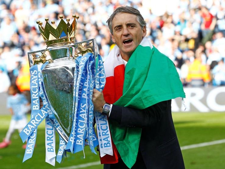 Wrapped in the UAE flag, Manchester City manager Roberto Mancini celebrates winning the Barclays Premier League.