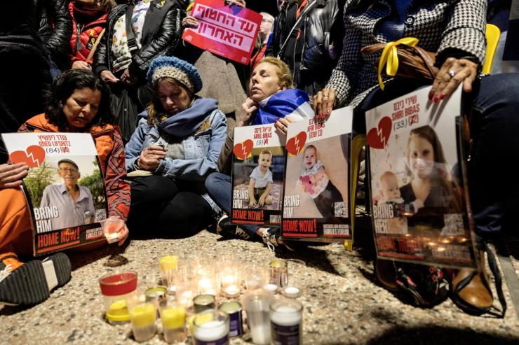 Israelis light candles and hold posters with images of Oded Lifschitz, Shiri Bibas and her two children, Kfir and Ariel Bibas.