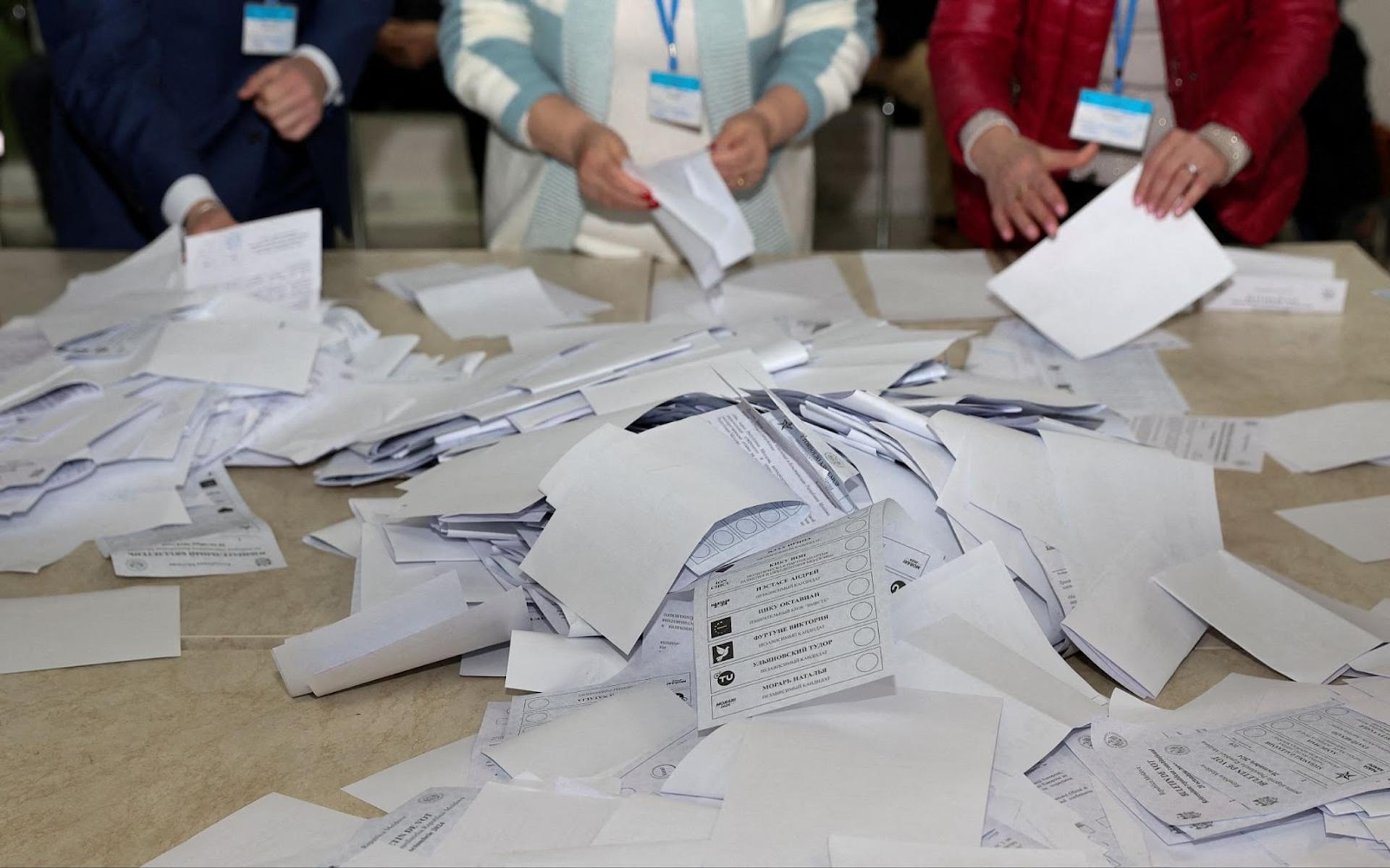 Members of an electoral commission count a pile of ballot papers after polling stations closed following Moldova’s presidential election and referendum on joining the EU